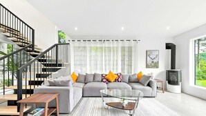 Ein modernes Wohnzimmer mit Treppe, einem Ecksofa, einem Glastisch und einem Kamin.