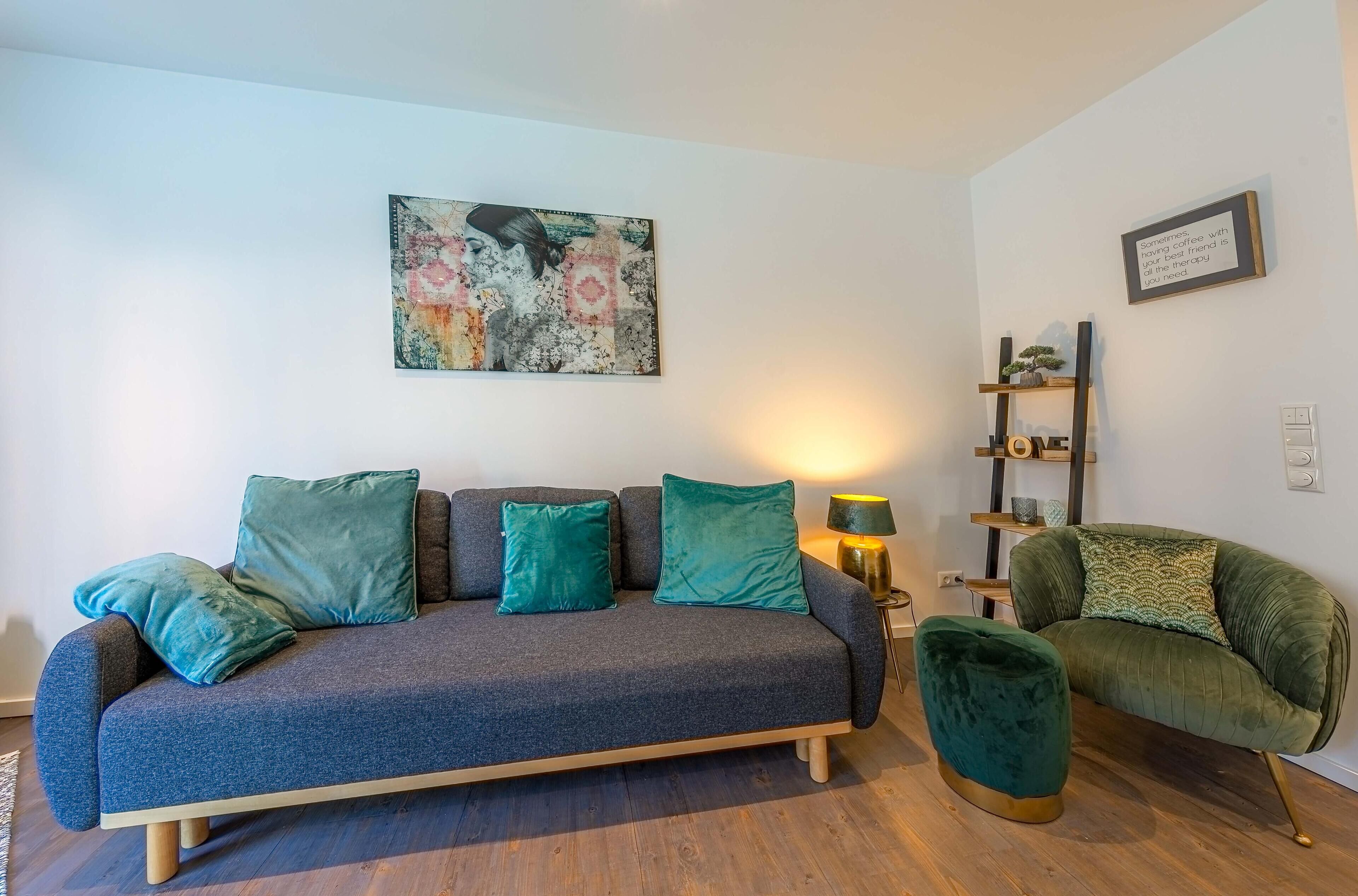 Una sala de estar moderna con un sofá gris, cojines color turquesa, un sillón verde y piso de madera.