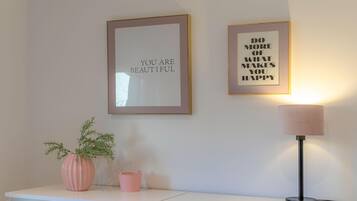 Eine Wand mit zwei gerahmten Motivationssprüchen sowie ein Schreibtisch mit einer Lampe und einer Topfpflanze.