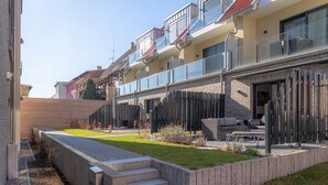 Un edifici residencial modern amb un balcó, zona d'estar a l'exterior i un jardí ben cuidat.