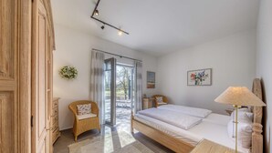 Quarto com cama, penteadeira, cadeira, mesa de cabeceira e abajur.