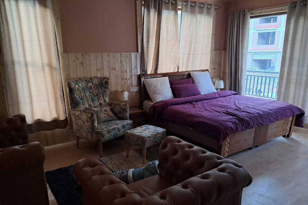 Quarto com cama, cadeira, mesinha e sofá.