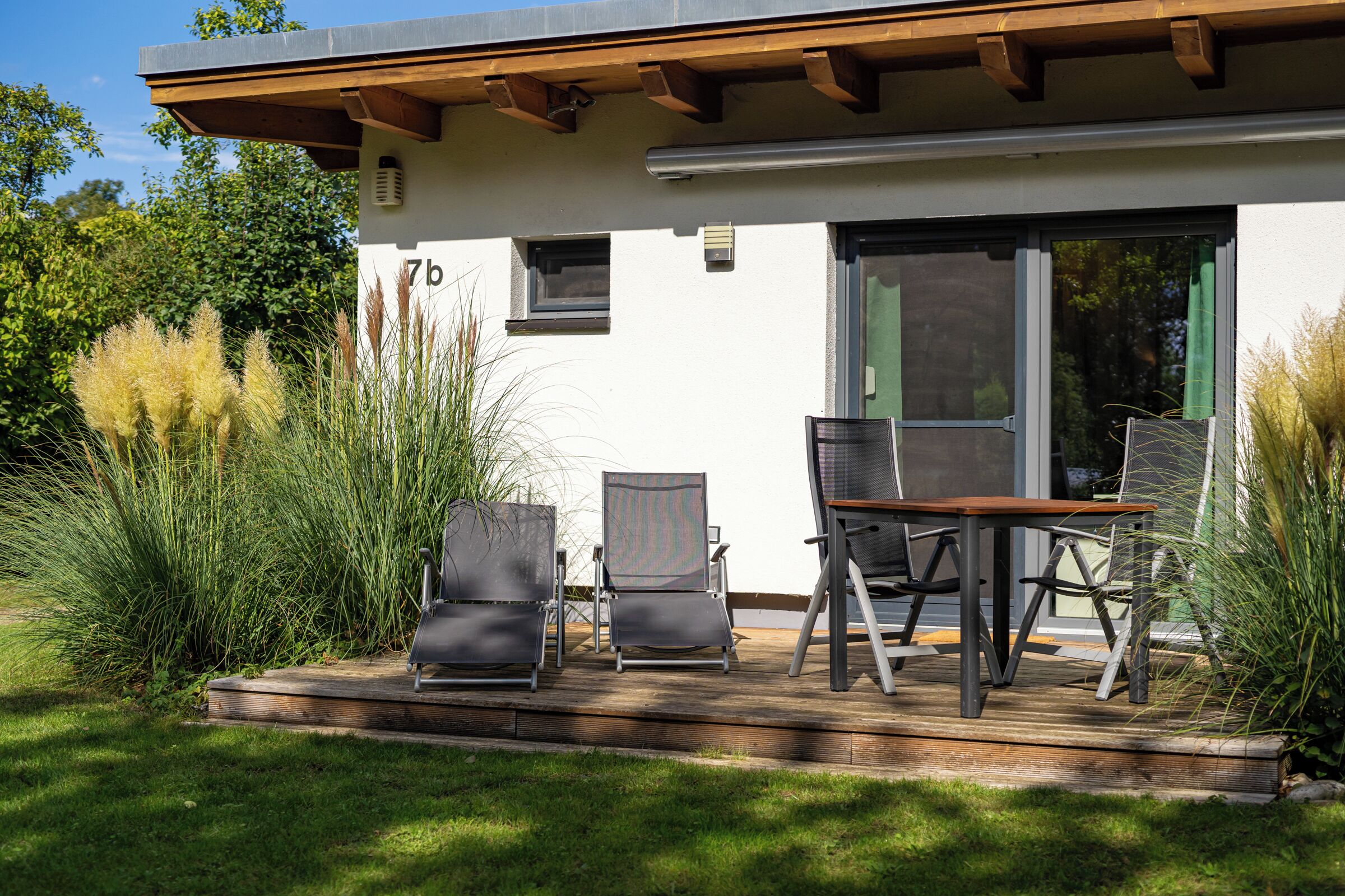A modern house with a deck, two chairs, and a table.