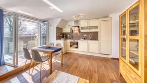 Une cuisine moderne avec un coin repas, de grandes fenêtres et un plancher en bois.