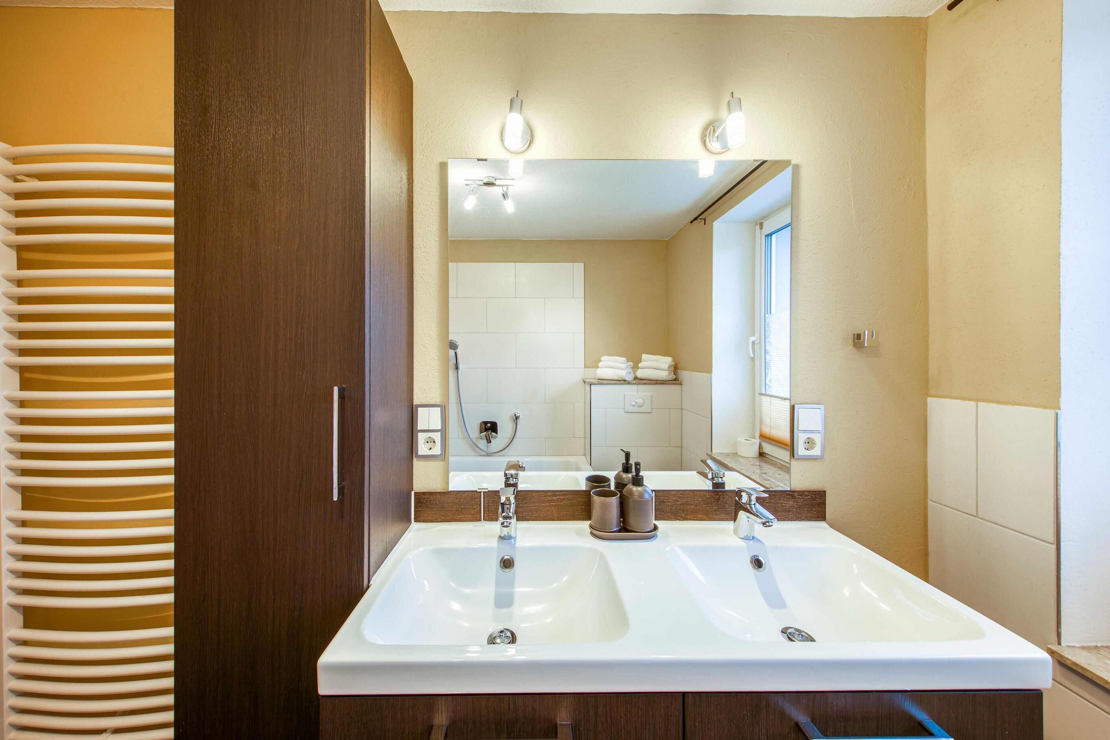 A bathroom with two sinks, a large mirror, and a shower.