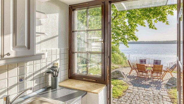 Una cocina con ventana que da a un patio con mesa y sillas.