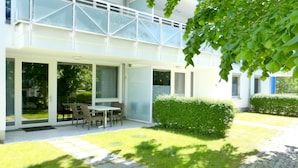 Un edificio moderno con ampie vetrate, un patio con mobili da esterno e un prato curato.