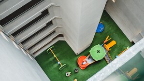 Zona de juegos infantiles con tobogán, columpios y una piscina pequeña.