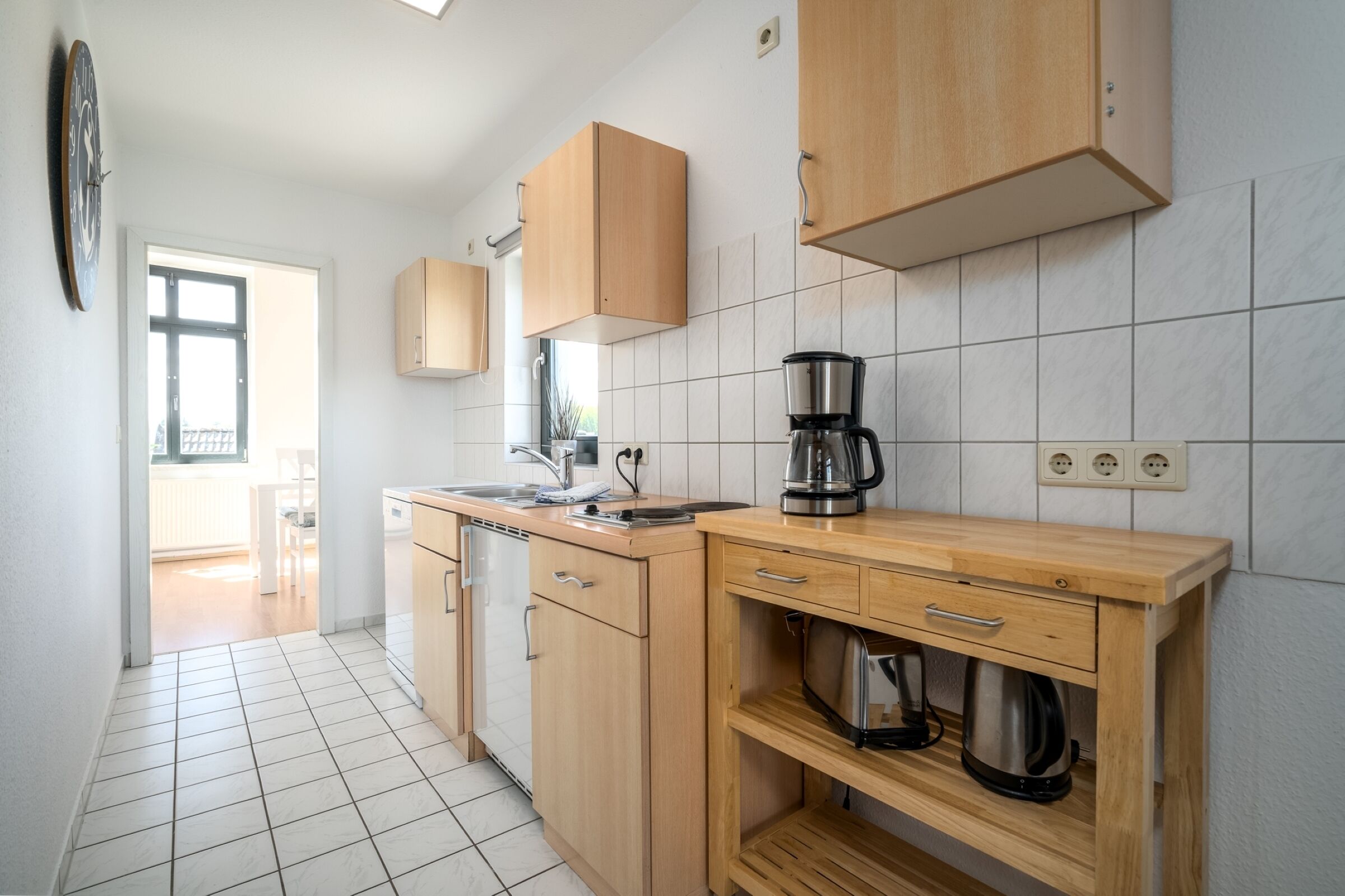 A modern kitchen with wooden cabinets, a coffee maker, and a dishwasher.