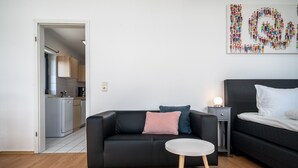 En moderne stue med en sort sofa, et rundt sofabord og et maleri på væggen.