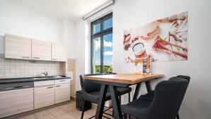 Eine moderne Küche mit Essbereich, ausgestattet mit einem Holztisch, schwarzen Stühlen und einem großen Fenster mit Blick auf die Stadt.