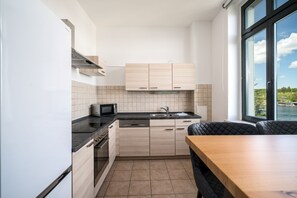Enjoy meals in this kitchen with an oven, sink, and microwave, adjacent to a dining area with a table and chairs.