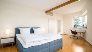 Une chambre moderne avec un grand lit, des tables de chevet, un bureau et une fenêtre.