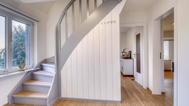 Una moderna scala con gradini in legno e una parete bianca.