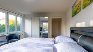 Una camera da letto con un letto grande, una sedia e vista all'esterno attraverso una finestra.