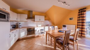 Uma cozinha com armários brancos, uma mesa de madeira e cadeiras.
