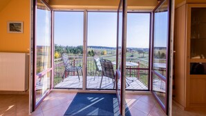 Quarto com uma grande porta de correr de vidro que dá para um deck externo com cadeiras e uma mesa.