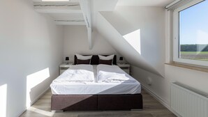 Une chambre avec une lucarne, un lit, des tables de chevet et une vue sur l’extérieur.