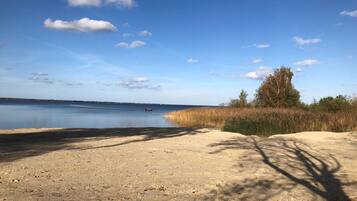 Ein sandiger Strand mit blauem Himmel und ruhigem Wasser.
