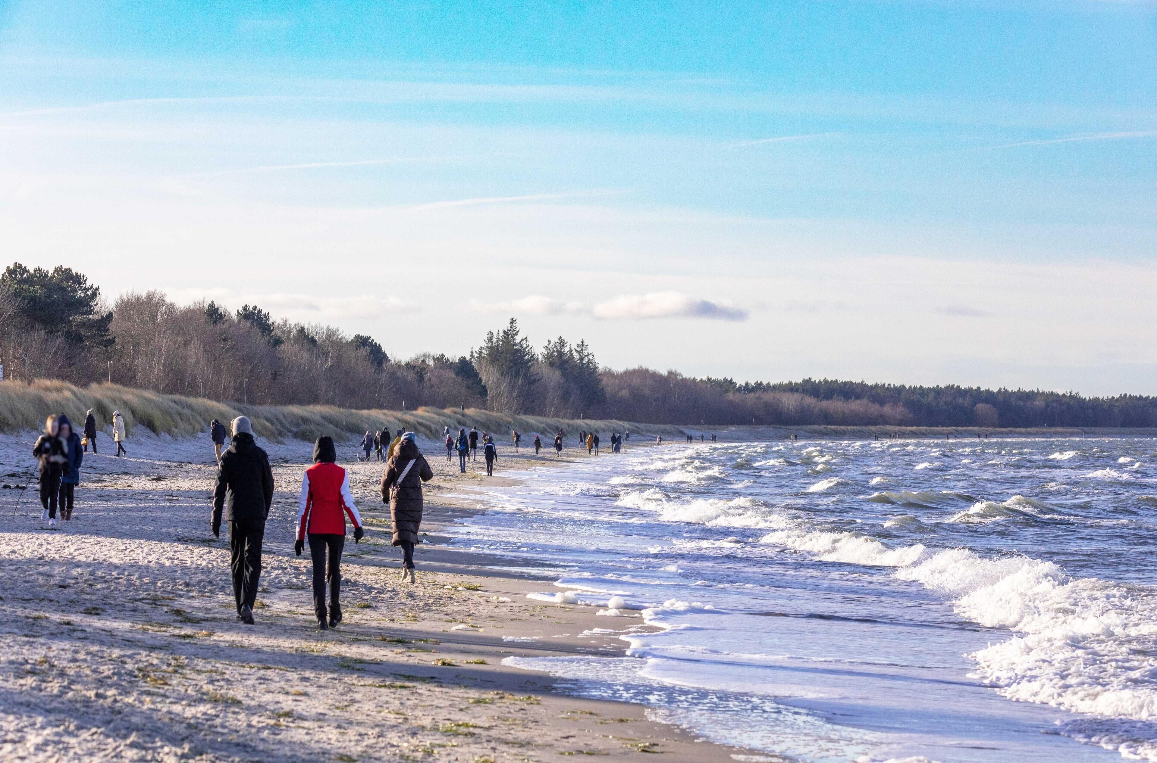 Een strand met mensen die langs de kust wandelen.