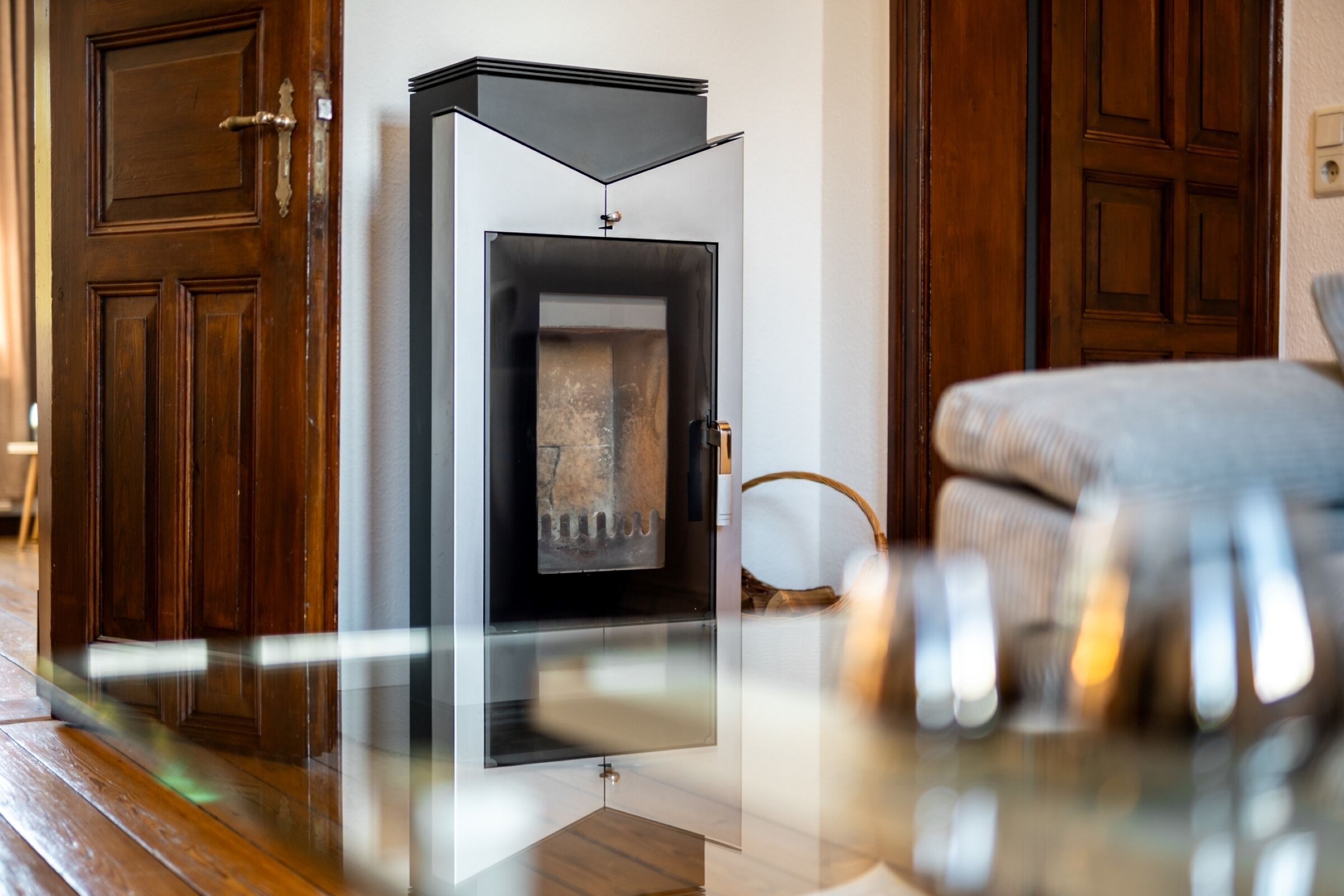 A modern room with a glass-fronted fireplace, wooden flooring, and a sofa.