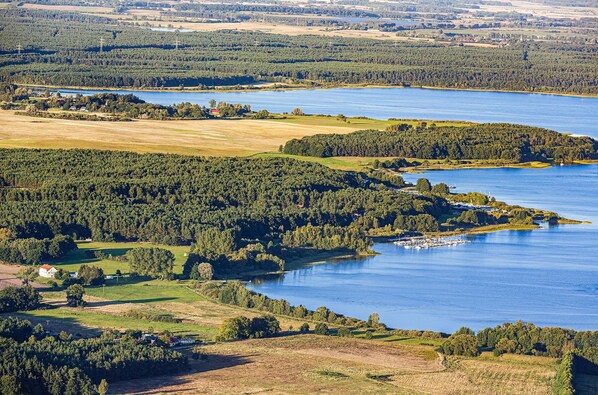 An aerial view of a lake surrounded by dense forests and fields.