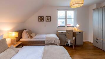 Une chambre avec deux lits, un bureau, une chaise, une armoire et une fenêtre.