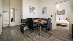 Una habitación moderna con una mesa de comedor de madera, sillas negras, un sofá y una cama.