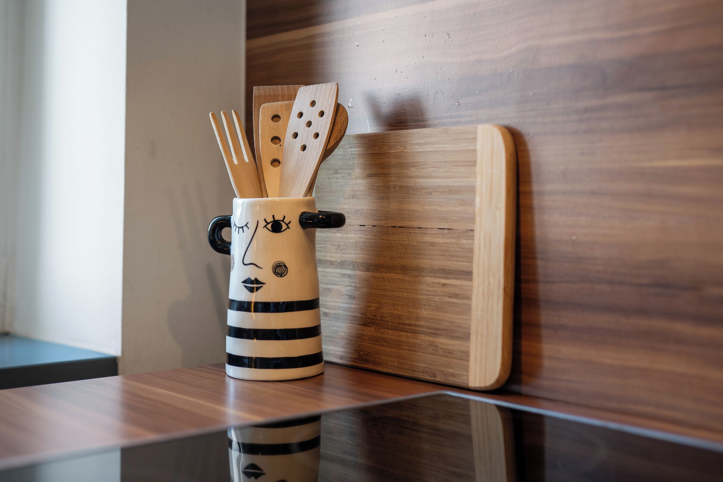 Un coin cuisine avec une planche à découper en bois et une tasse décorée d’un visage.