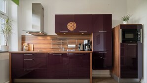 Una cocina moderna con armarios oscuros, encimera de madera y horno empotrado.
