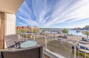 A balcony with a table and chairs overlooking a marina with boats and a parking area. - "Hafenglück" Vacation Rental in Waren (Müritz) for 2–6 people, with a balcony (Waren (Müritz))