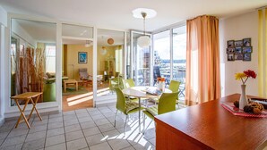A modern living room with a dining area, large windows, and a view of the city.