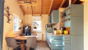 Una cocina con vigas de madera en el techo, una mesa de comedor con sillas y armarios azul claro.