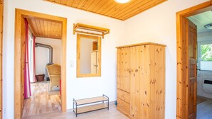 Een kamer met houten vloeren, een houten garderobe, een spiegel en een bankje.