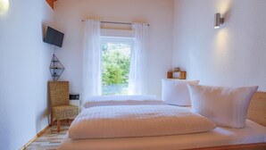 Une chambre à coucher avec un lit, une chaise, une télévision et une fenêtre avec des rideaux.