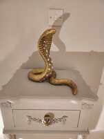 Un aparador blanco con una figurita de serpiente decorativa en la parte superior.