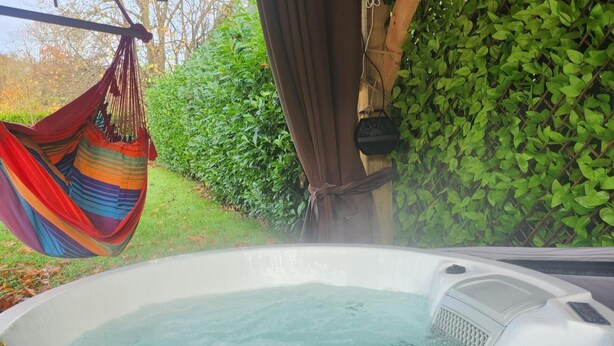 Un bain à remous avec un hamac et de la verdure en arrière-plan.