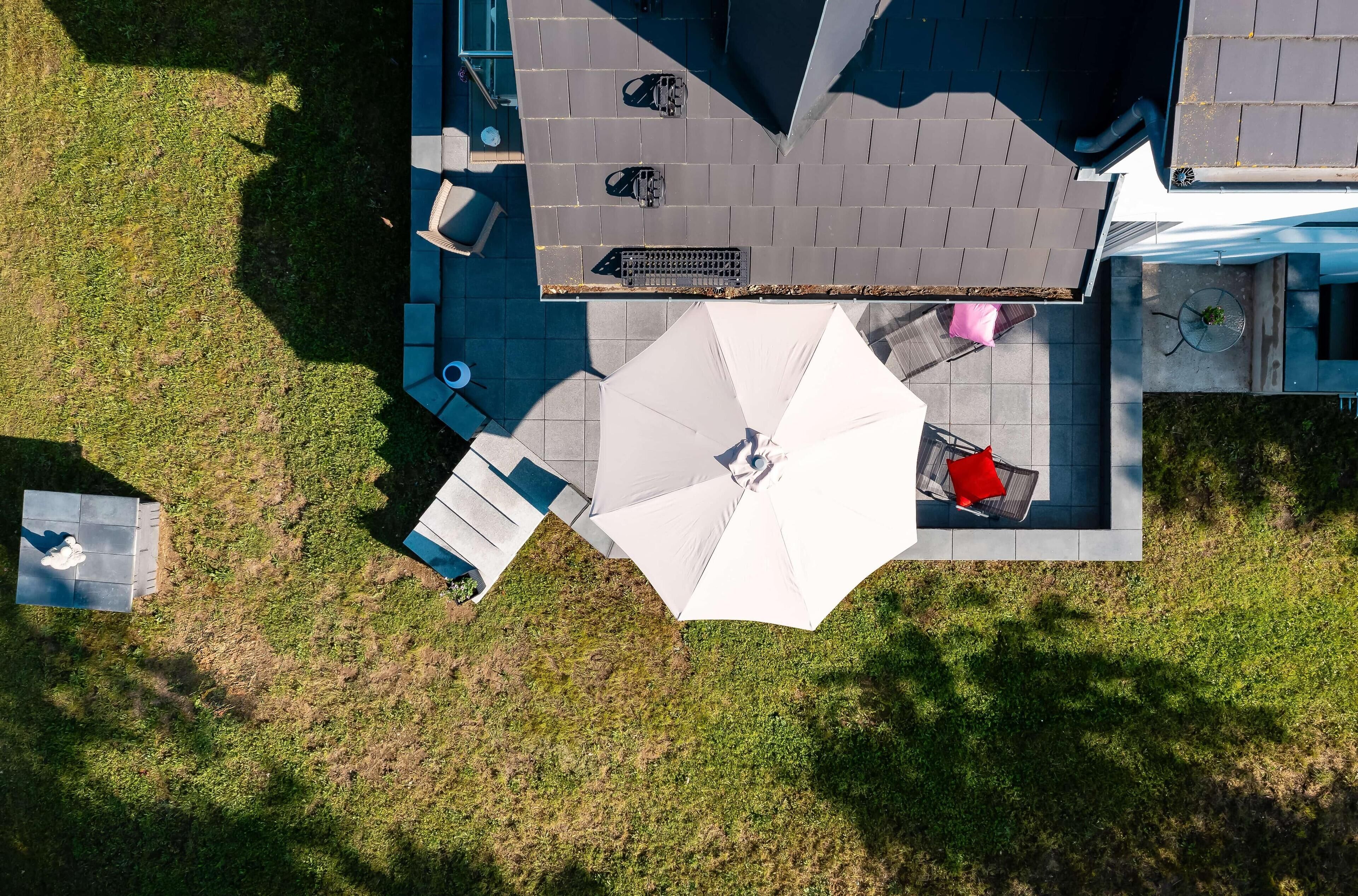 An aerial view of a patio area with a seating arrangement, a table, and a large umbrella.