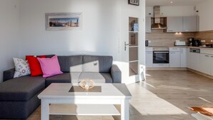 A modern living room with a grey sectional sofa, a white coffee table, and a painting on the wall. - "SchönSicht" Vacation Home in Alt Schwerin, Right on the Lake (Alt Schwerin)