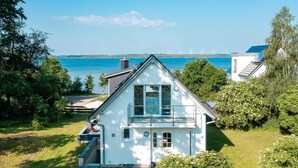 A white house with a balcony, surrounded by greenery and a view of the sea. - "SchönSicht" Vacation Home in Alt Schwerin, Right on the Lake (Alt Schwerin)