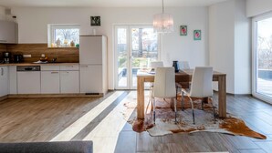 A modern kitchen with white cabinets, a wooden countertop, and a dining area with a table and chairs. - "SchönSicht" Vacation Home in Alt Schwerin, Right on the Lake (Alt Schwerin)