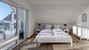 A bedroom with a large window, a bed, bedside tables, a dresser, and a mirror on the wall. - "SchönSicht" Vacation Home in Alt Schwerin, Right on the Lake (Alt Schwerin)
