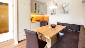 Una cocina moderna con armarios blancos, una mesa de madera y un sofá gris.