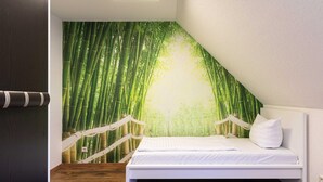 Ein Schlafzimmer mit einem Bett, weißer Bettwäsche und einer Wandmalerei von einem Bambuswald.