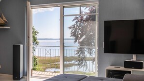 Ein modernes Wohnzimmer mit großem Flachbildfernseher, einer Couch und einem Balkon mit Blick auf das Wasser.