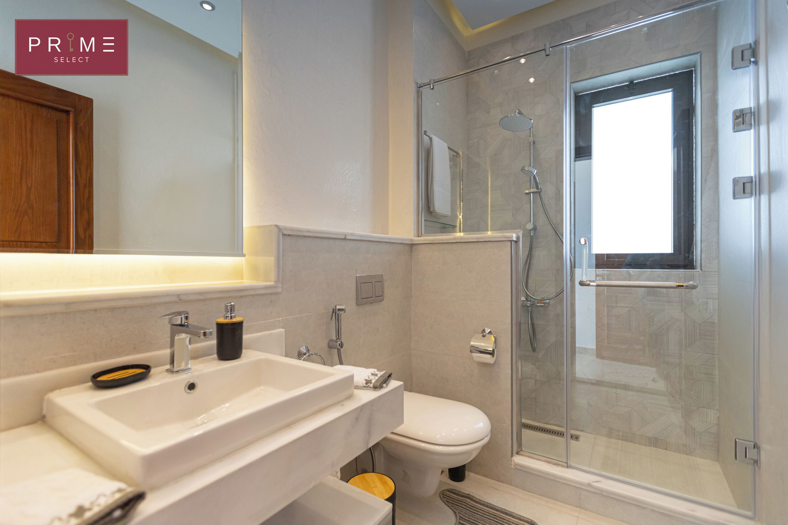 A modern bathroom with a glass-enclosed shower, a white sink, and a toilet.