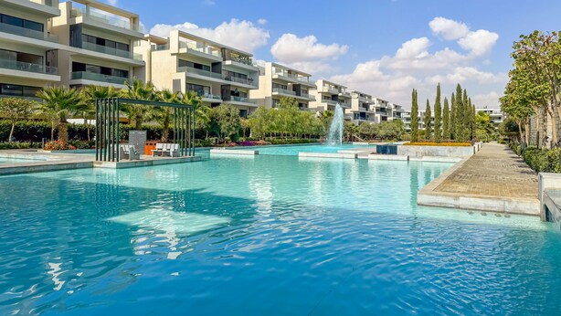 Un hotel moderno con una grande piscina, area relax all'aperto e una fontana.
