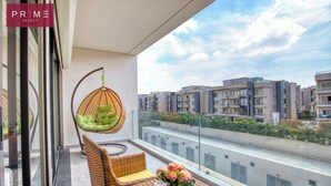 Un balcone con mobili in vimini, una sedia a dondolo e un tavolino con fiori.