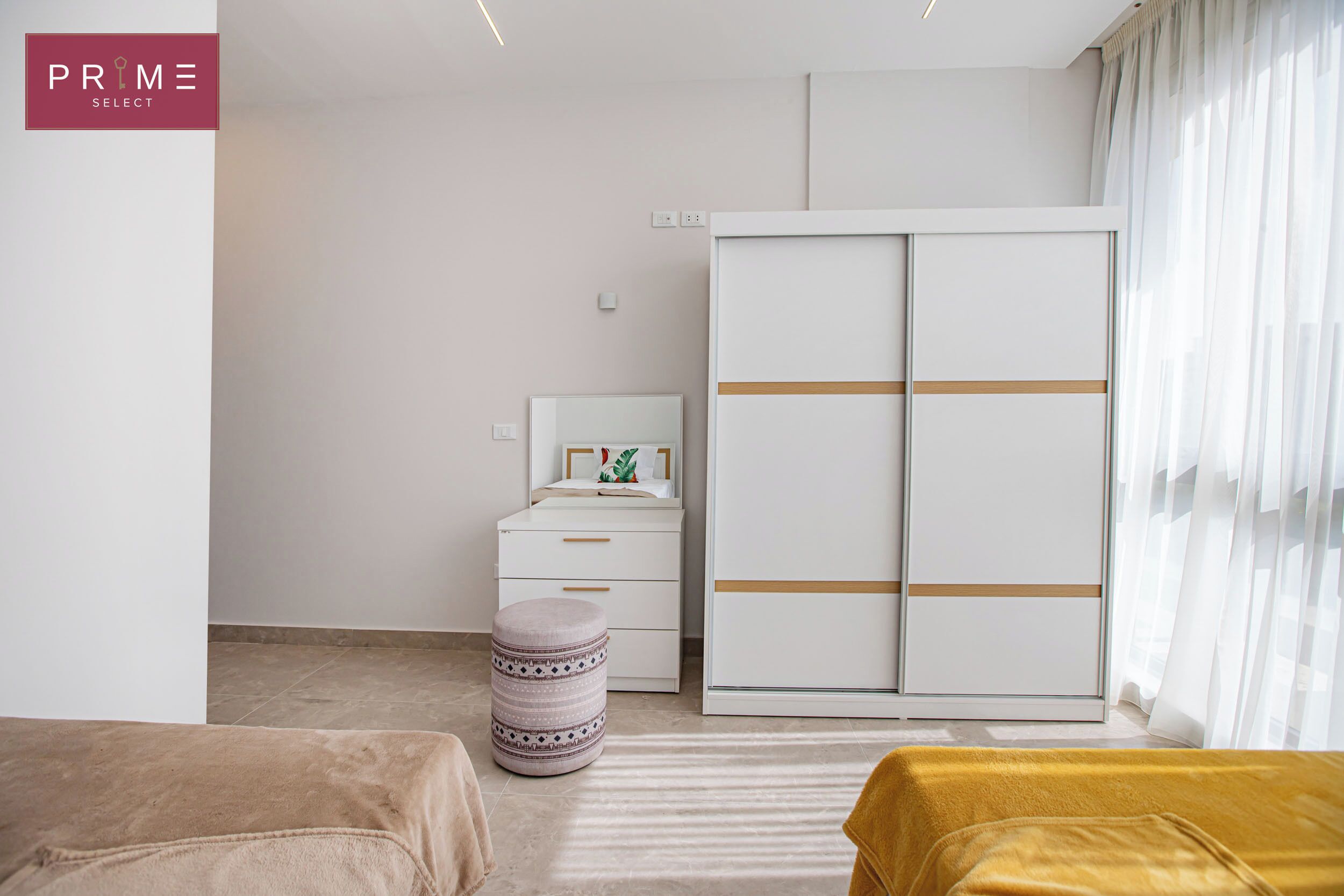 A modern bedroom with a bed, a wardrobe, a nightstand, and a small stool.