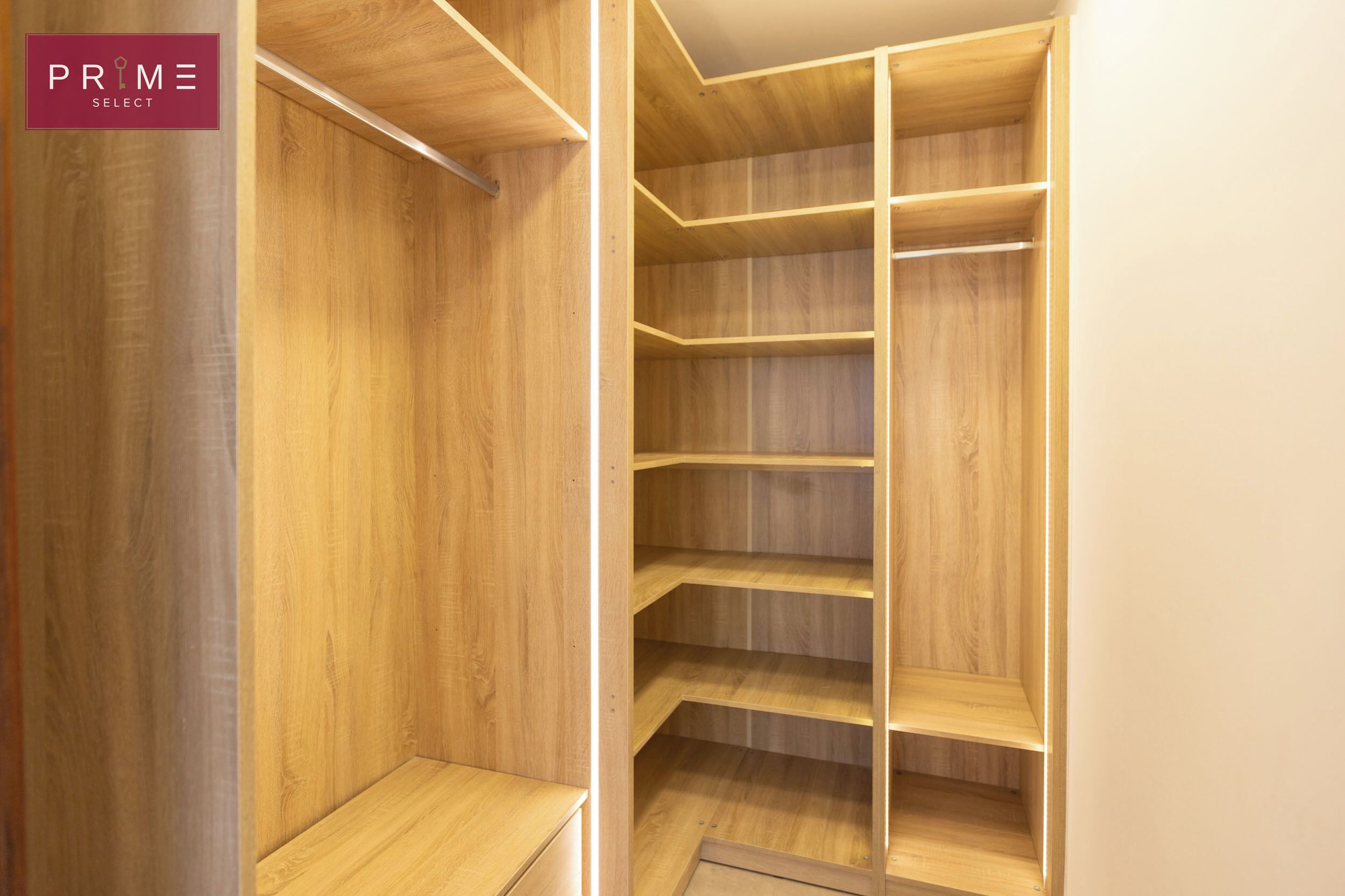 A walk-in closet with multiple wooden shelves and a hanging rod.